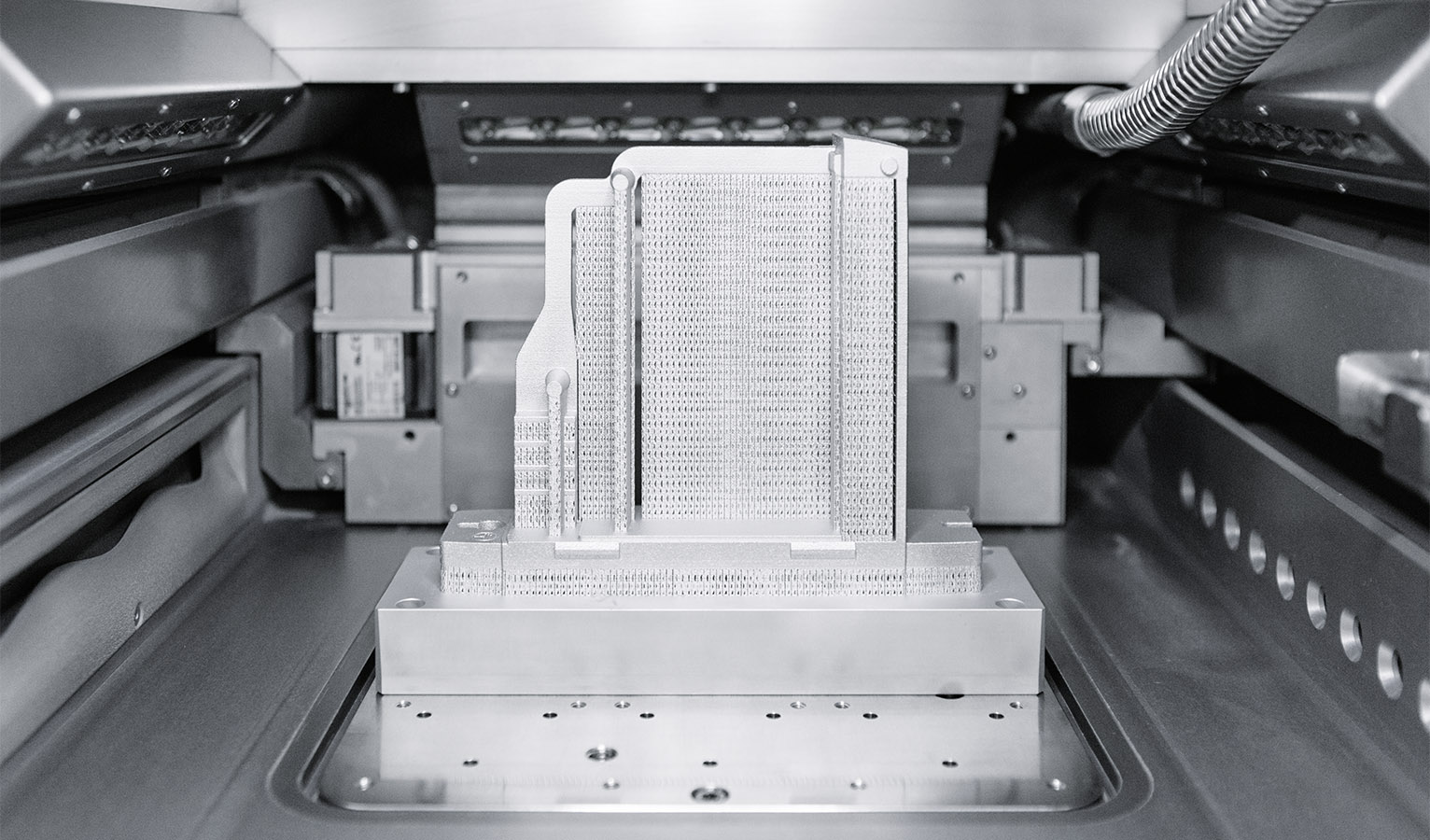 Un composant imprimé en aluminium dans l’espace de fabrication : Les supports en nids d’abeilles et la plaque de substrat, sur laquelle le composant est soudé, sont retirés manuellement après l’impression