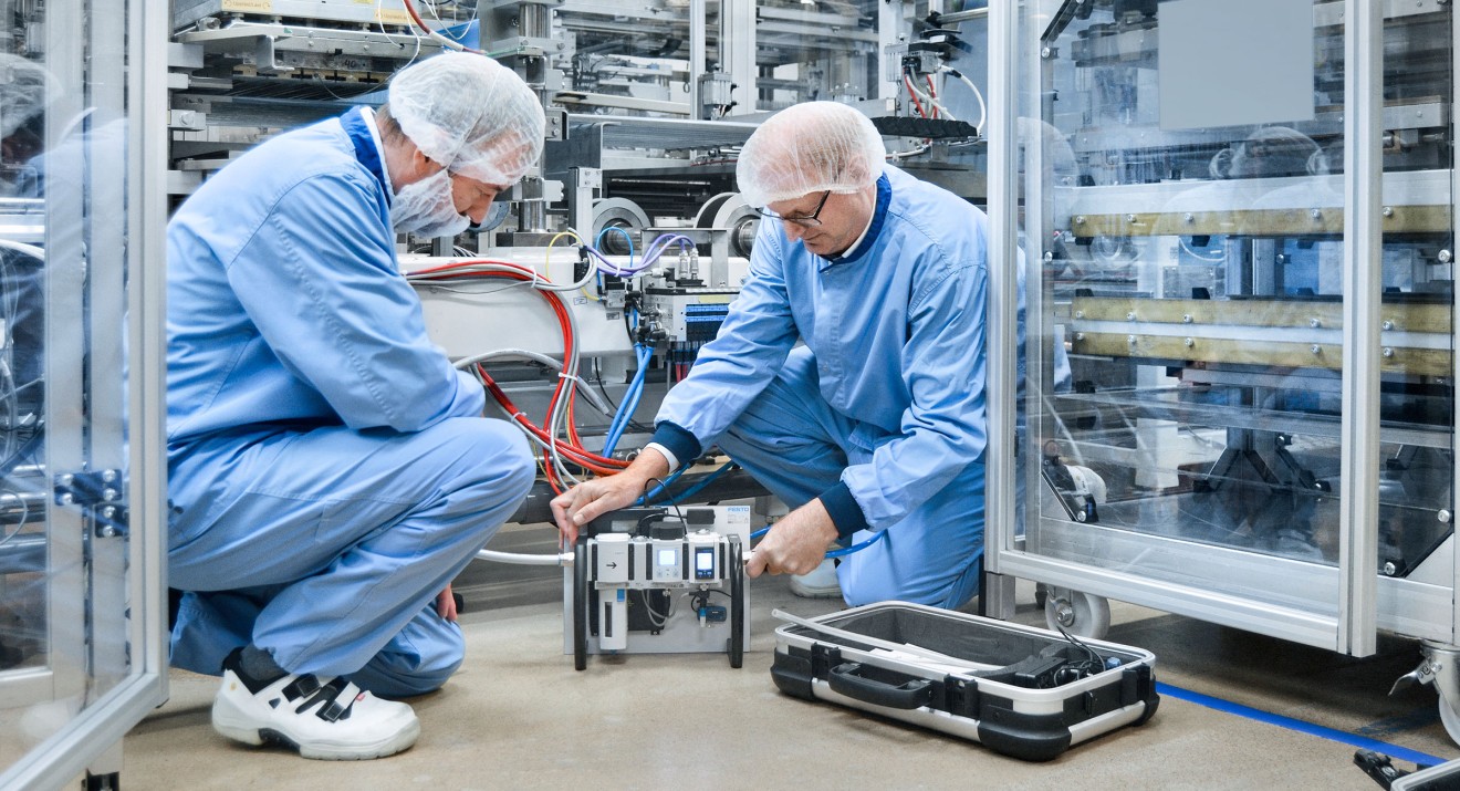 Bo Lilja (derecha), experto en eficiencia energética de Festo Suecia, mide el consumo de aire comprimido en la línea de producción con la caja de medición de caudal SFGA.