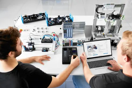 Dva studenti pracují s automatizačními školicími systémy a prohlížejí si data na notebooku.
