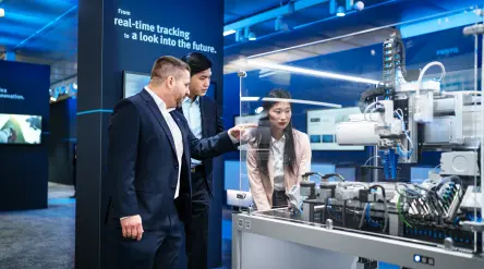 Festo Kunden lassen sich ein interaktives Display auf der Messe erklären.