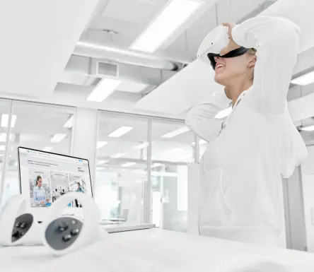 Person, die ein VR-Headset in einem hellen Schulungsraum einstellt, um die 3D-Pneumatik-Simulationssoftware für immersives Lernen zu nutzen.