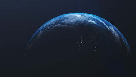 Visão panorâmica da Terra no espaço, destacando um hemisfério escuro com visíveis faixas de luz azul e áreas urbanas iluminadas